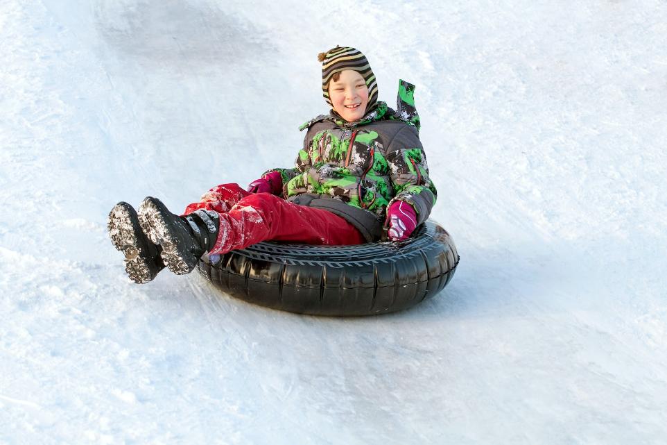 a young boy riding a snow tube down a snow covered slope